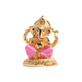 Golden ganesha idol seated, adorned with pink details.