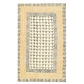 A rectangular rug with a boho-inspired geometric block-printed pattern in beige, black, and gray tones.