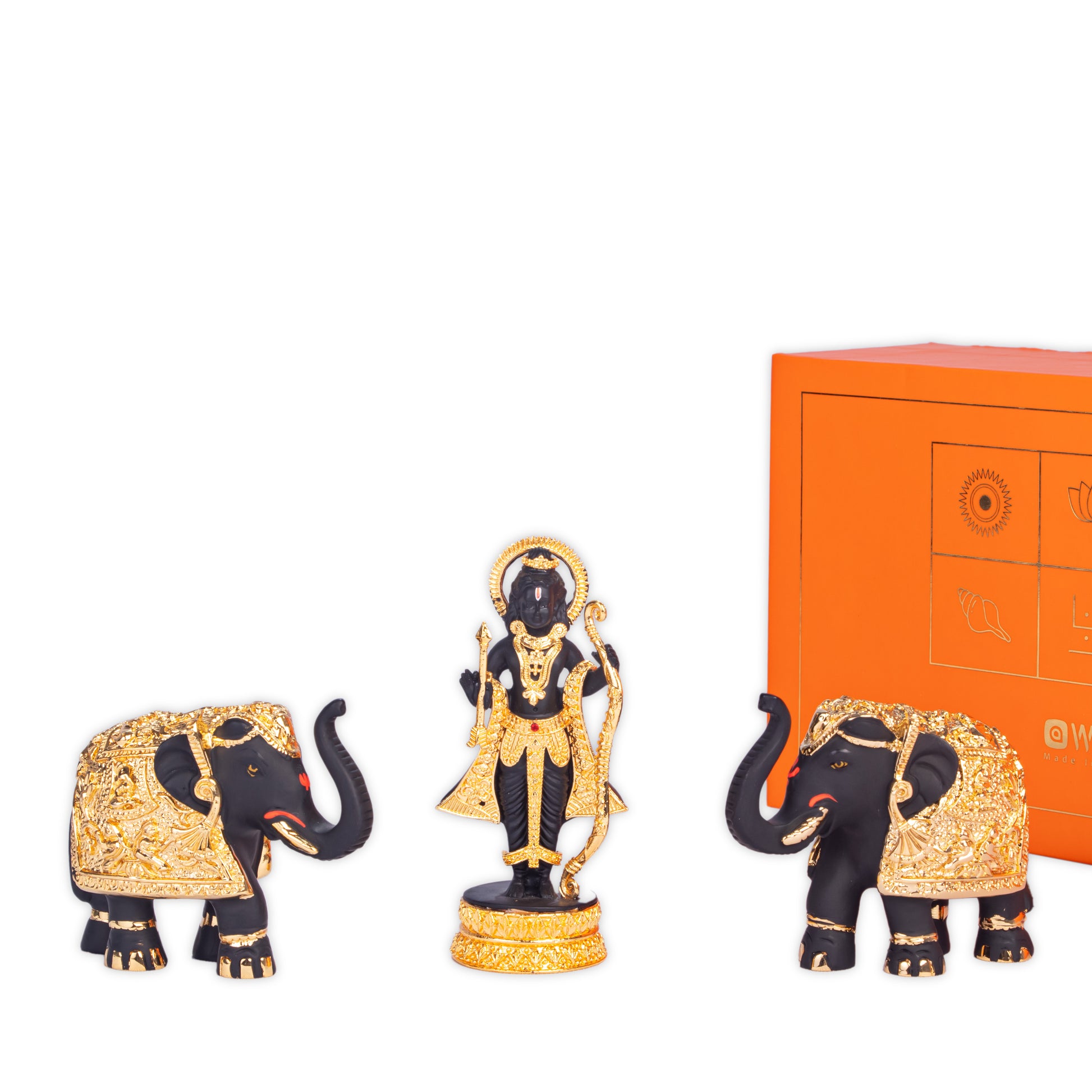 A black and gold Ram Lalla idol stands prominently in the center, flanked by two similarly styled black and gold elephant statues with their trunks raised. An orange decorative box is visible in the background to the right.