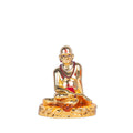 A golden, intricately detailed idol of Swami Samarth, seated in a meditative posture, adorned with a tilak and mala, on a decorative base, set against a plain white background.