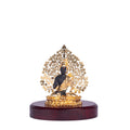 A black and gold Lord Buddha statue for home decor is seated in a meditative pose on a polished, dark wooden base. The statue features an intricate golden Bodhi tree design as a backdrop.