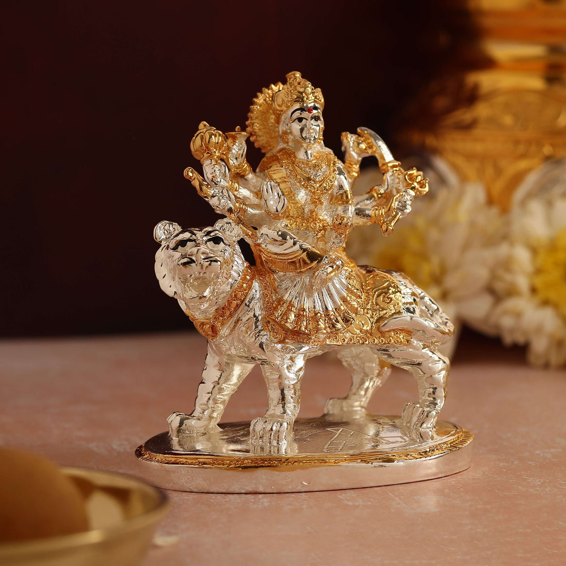 Gold and silver plated idol of Goddess Durga seated majestically on her lion mount.