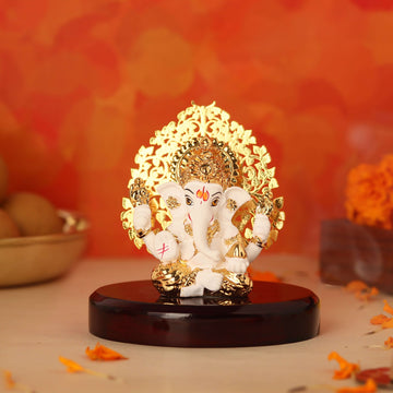 A Ganesha idol with a Kalpavriksha Tree, 3 inches tall, featuring a white and gold finish and a glossy wooden base.