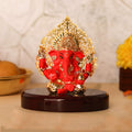 A red and gold Ganesha Idol with a Kalpavriksha Tree, approximately 3 inches in height, seated on a glossy dark wooden base.