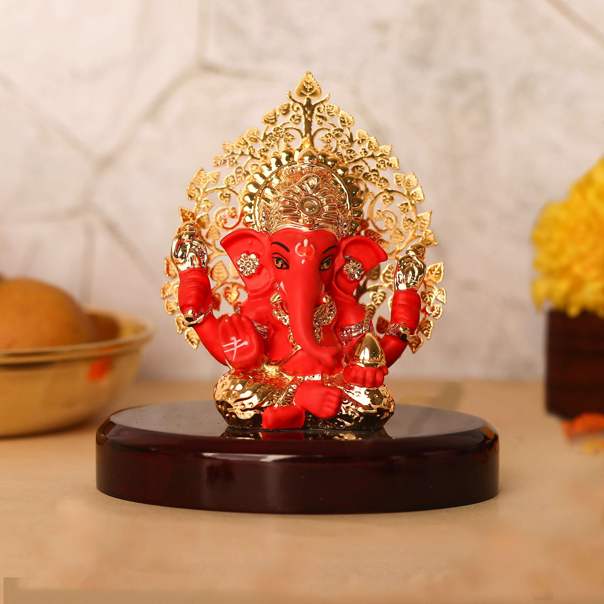 A red and gold Ganesha Idol with a Kalpavriksha Tree, approximately 3 inches in height, seated on a glossy dark wooden base.