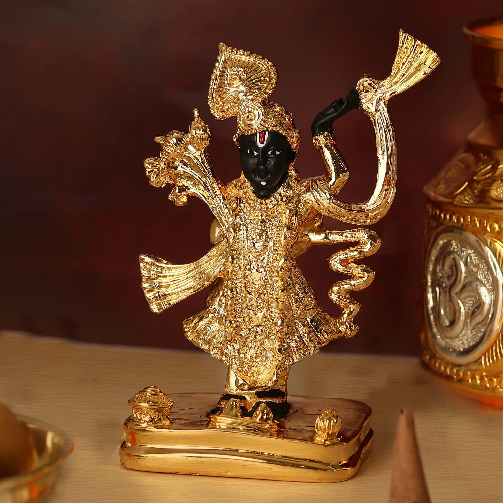 A golden idol of Lord Shreenath Ji, a form of Lord Krishna, with a dark (possibly black or blue-black) face, adorned with intricate gold-colored clothing and ornaments, standing on a golden base.
