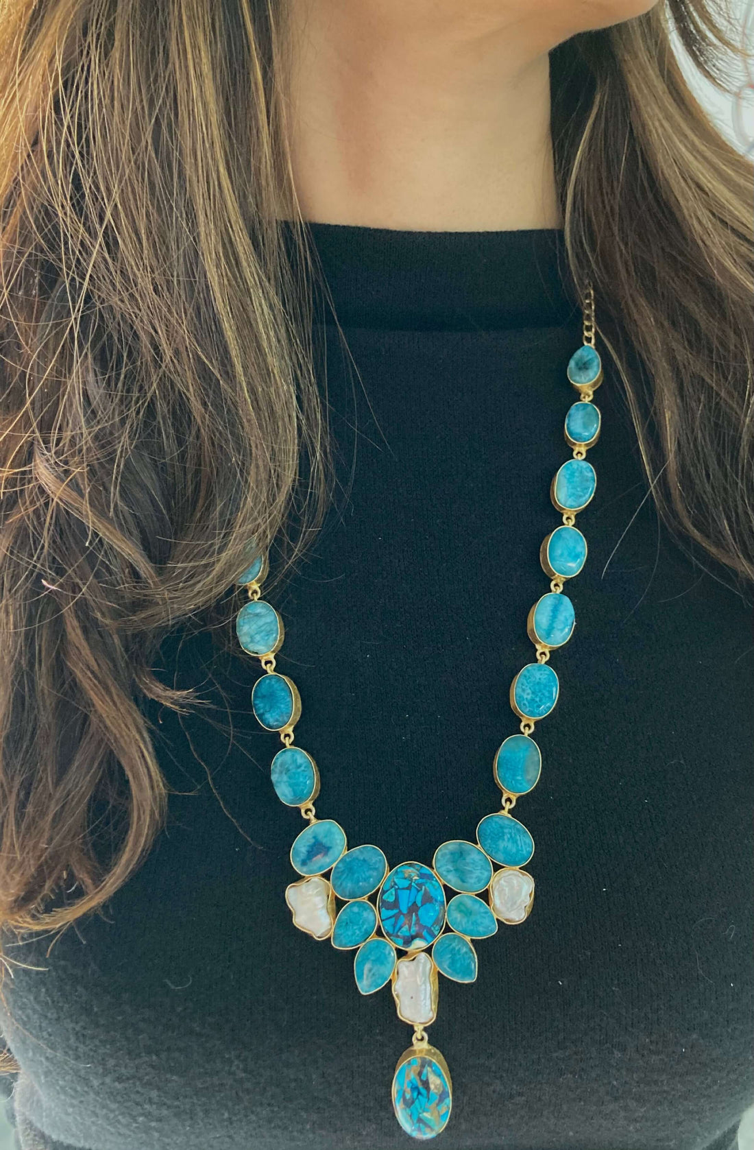 A long necklace with a multi-stone design featuring blue and green beads, strung together on a chain.