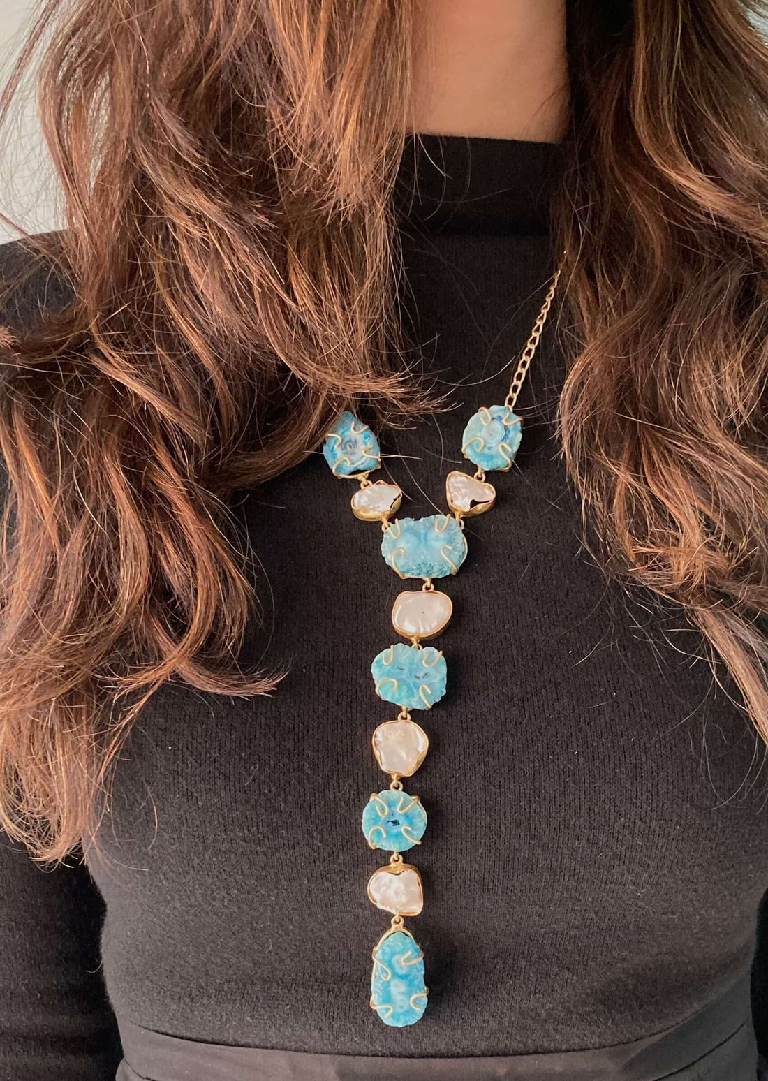 A long necklace with a multi-stone design featuring blue and green beads, strung together on a chain.