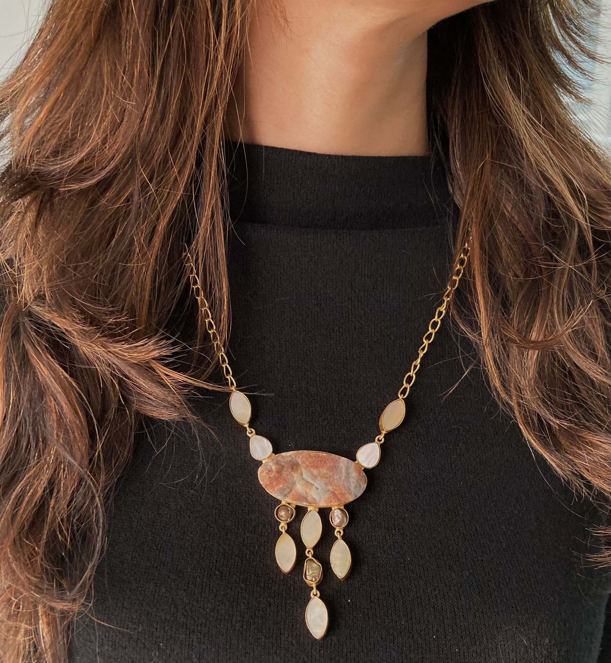 A long necklace with a multi-stone design featuring piech beads, strung together on a chain.