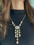 A long necklace with a multi-stone design featuring white beads, strung together on a chain.