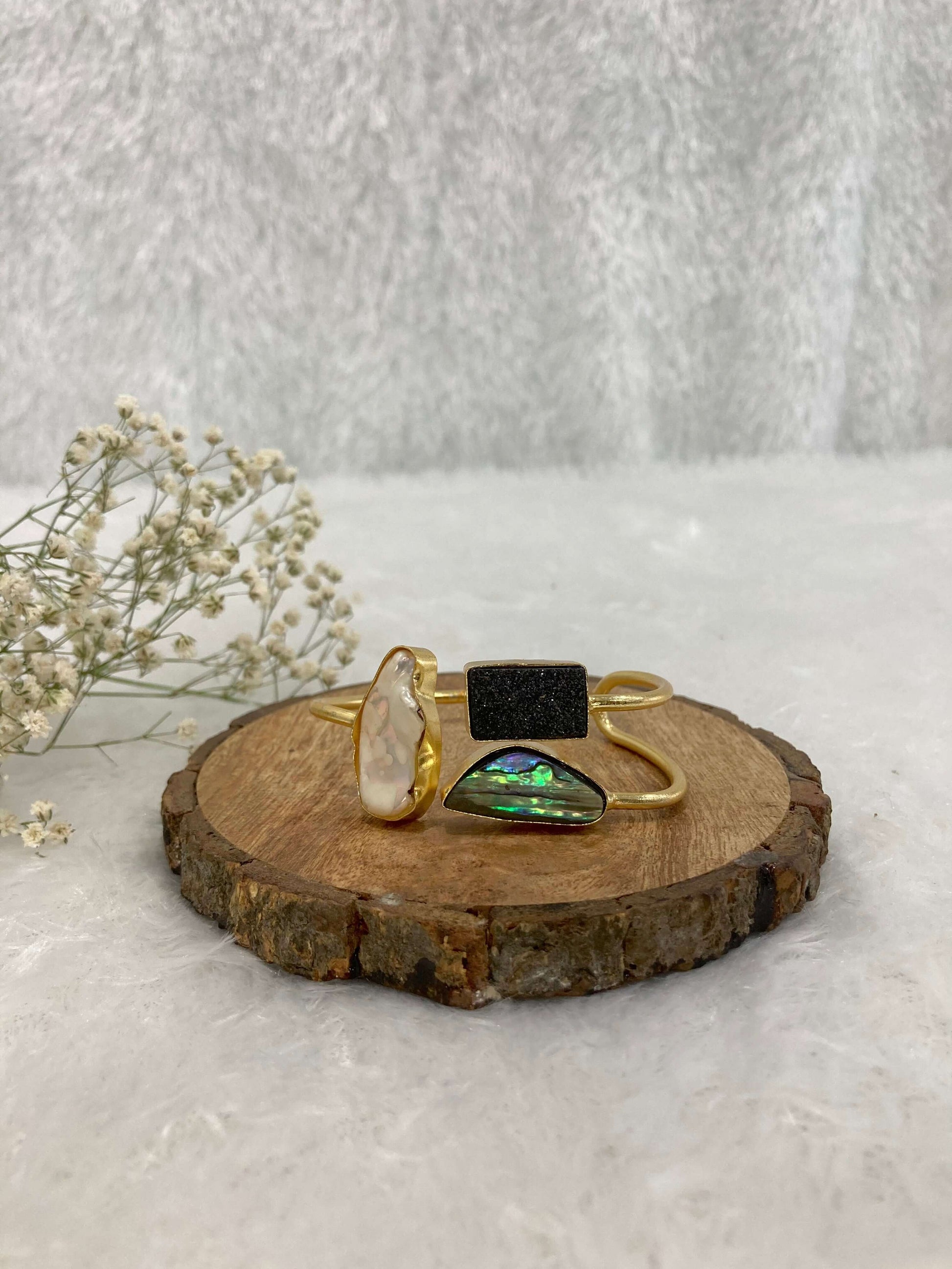 white, black and multicolor Stone adjustable ear cuff on the wooden base