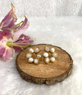 Six white earrings on the wooden base