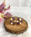 Six white and purple stone earrings on the wooden base
