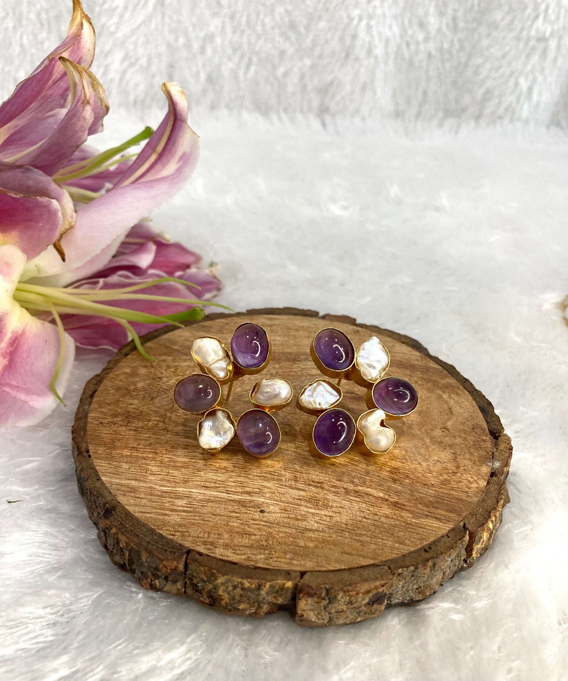 Six white and purple stone earrings on the wooden base