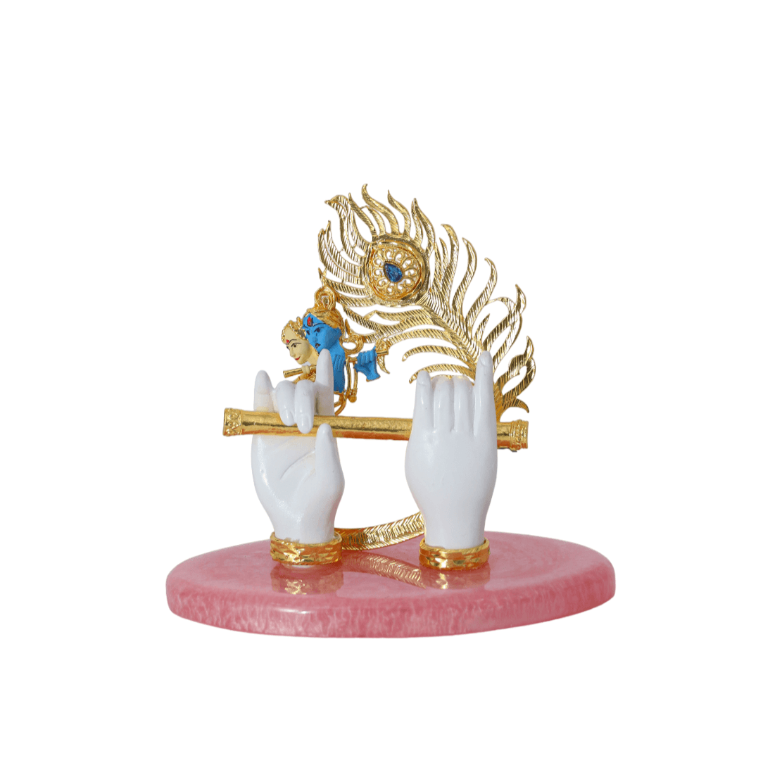 A decorative idol featuring Lord Krishna's hands in white holding a golden flute, with a golden peacock feather adorned with a blue eye-spot behind them, all mounted on a polished pink base.