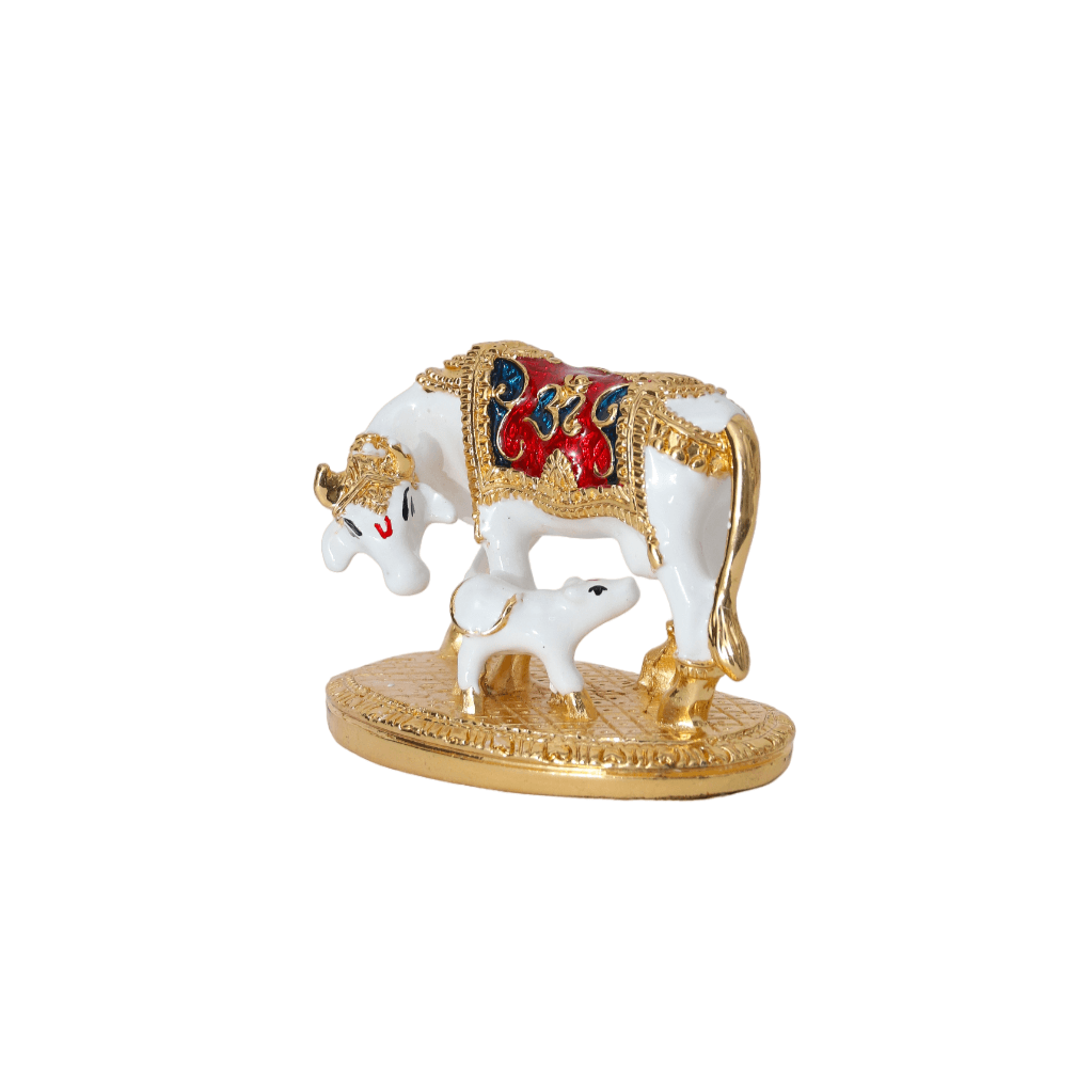 A white and gold Kamadhenu cow statue with a calf, representing prosperity, abundance, and positive energy in Hindu mythology. The cow has ornate detailing, and the idol stands on a gold-colored base.