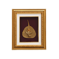 Framed artwork depicting a small, metallic Lord Ganesha idol resting on a golden or gilded Peepal leaf, set against a deep red background within an ornate gold picture frame.