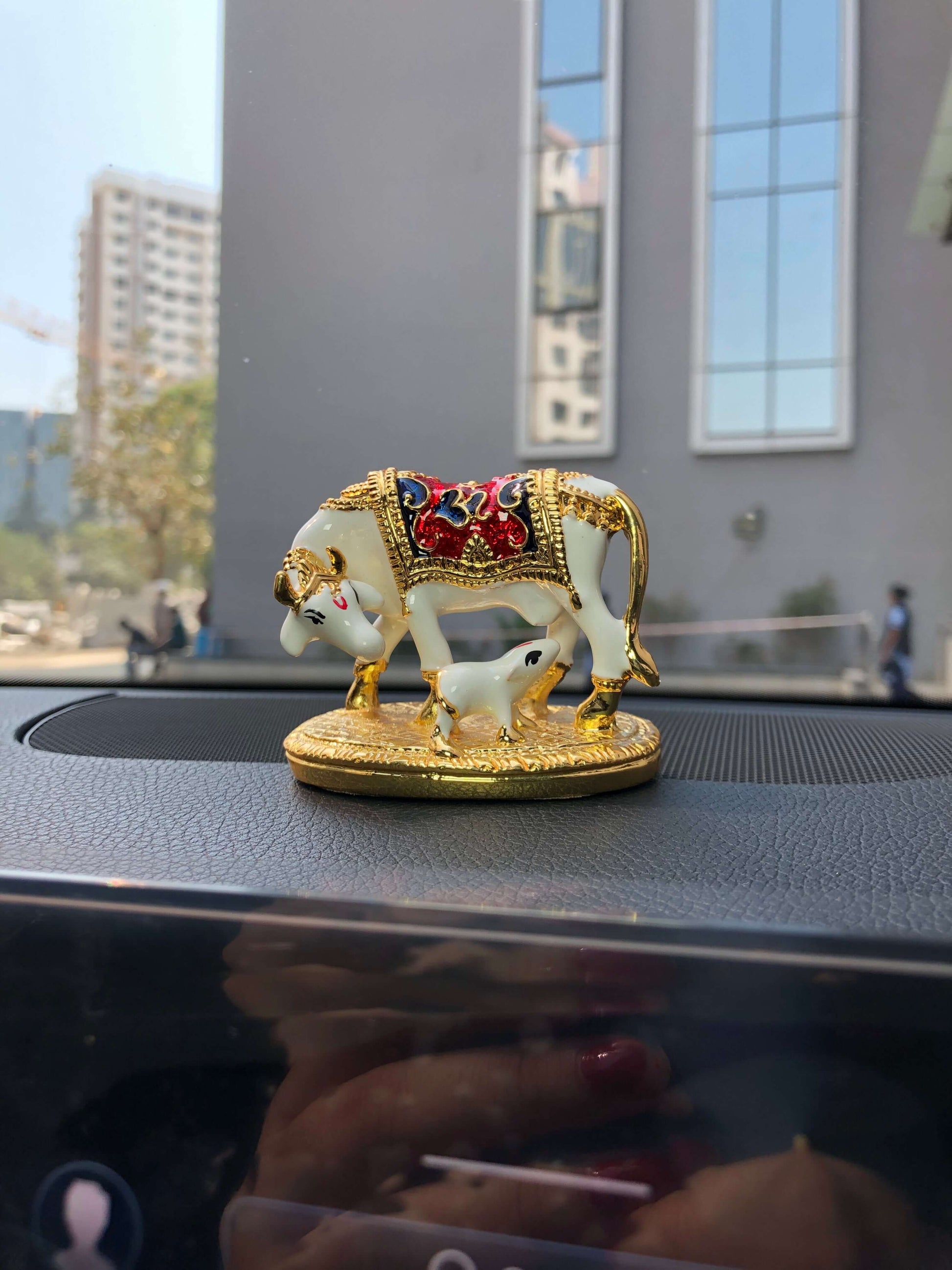 Kamadhenu cow and calf idol on the car dashboard.