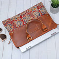 Hand Held Leather with block print laptop sleeve Maroon with sunglasses and small tree pot around it.
