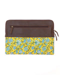A leather laptop sleeve with a yellow floral block print