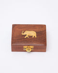 A small, rectangular, handcrafted wooden jewelry box with a brass latch on the front and a brass elephant inlaid on the lid. The wood has a natural grain and a polished finish.