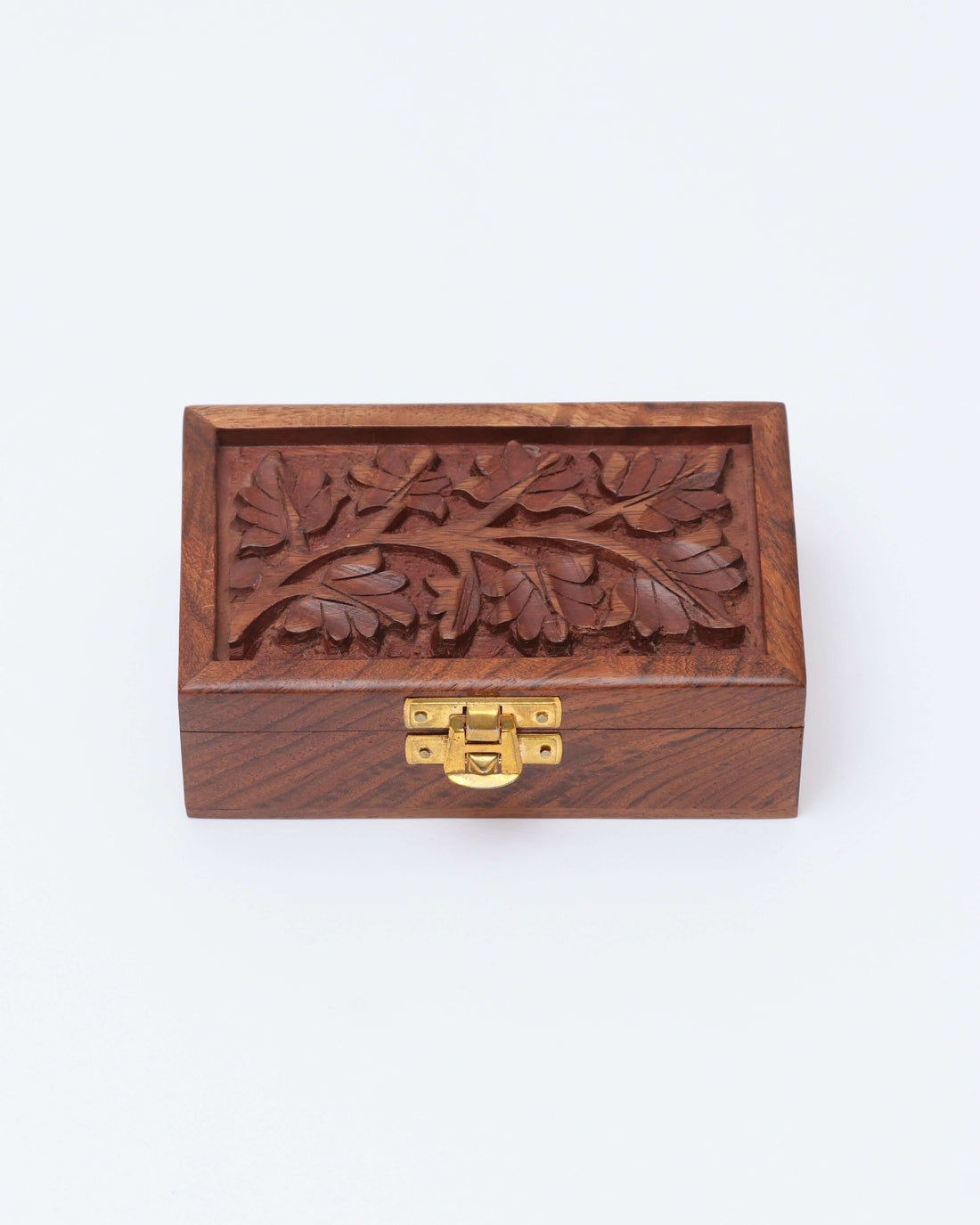 A small, brown wooden box is shown with a brass latch on the front. The lid of the box features a handcrafted floral engraving of leaves and branches.