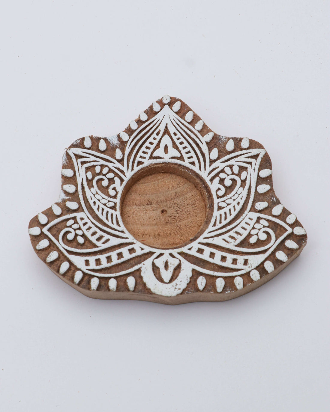 A wooden tealight holder with a floral pattern and a central opening for the candle.