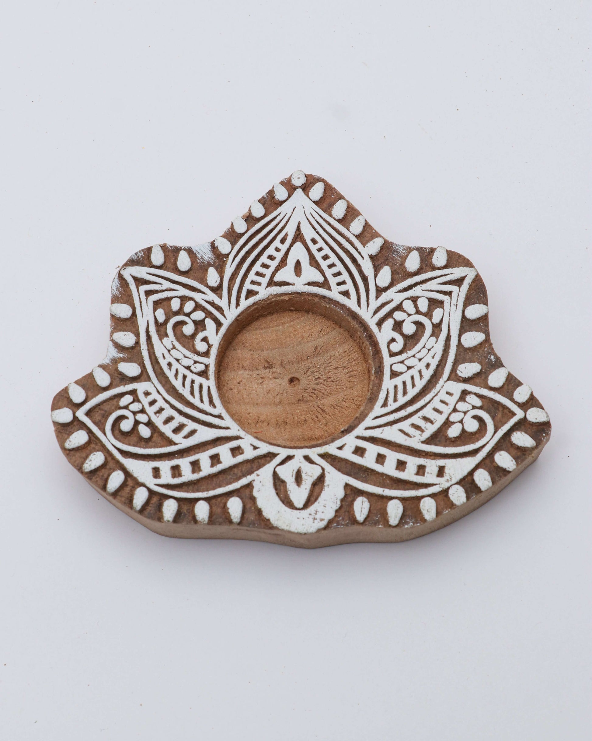 A wooden tealight holder with a floral pattern and a central opening for the candle.