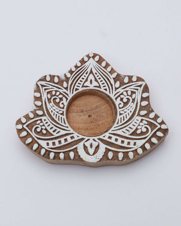 A wooden tealight holder with a floral pattern and a central opening for the candle.