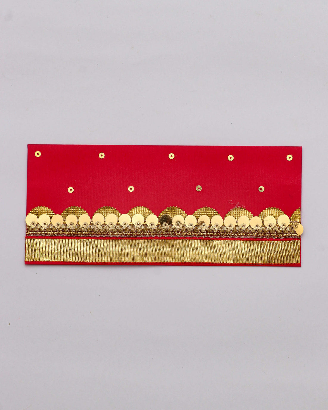 An orange Shagun envelope with gold and black embellished trim and a fringe of gold thread along the bottom. The envelope is also decorated with small gold sequins scattered across the top half.