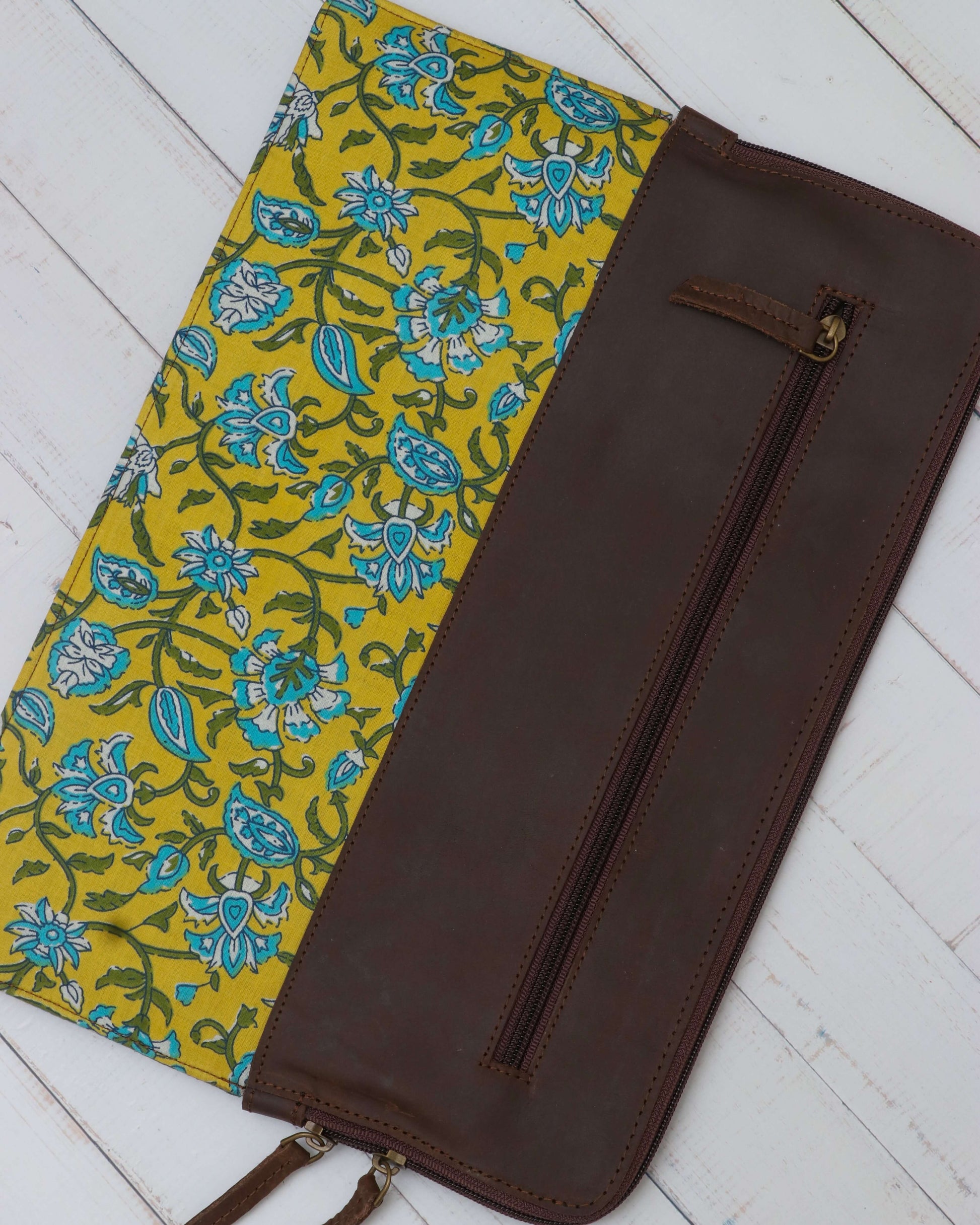 A leather laptop sleeve with a yellow floral block print on the lower half