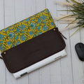 A leather laptop sleeve with a yellow floral block print on the lower half with Black mouse on the otherside.
