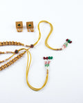 A set of traditional gold-plated jewelry, including a pair of square earrings with green stones and a matching necklace. The necklace is a multi-strand design with intricate gold beads and a decorative tassel-like closure featuring red, green, and white beads.