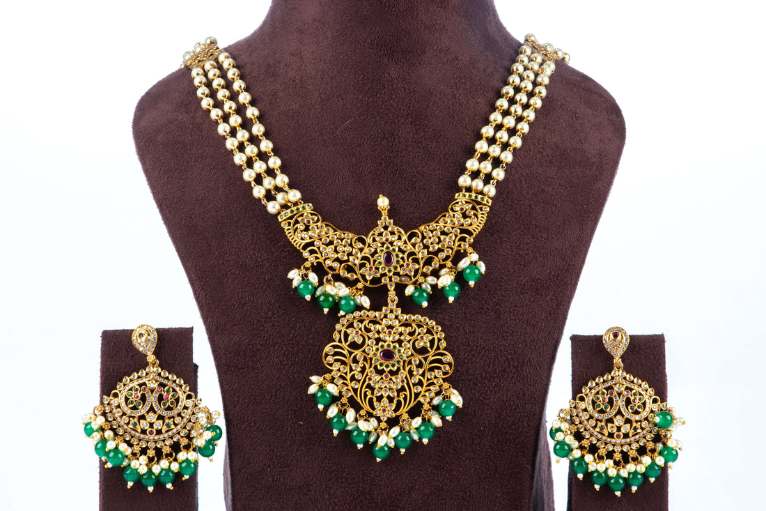 A necklace set with white pearl cascade design and green pearl pendant, displayed on a mannequin bust.