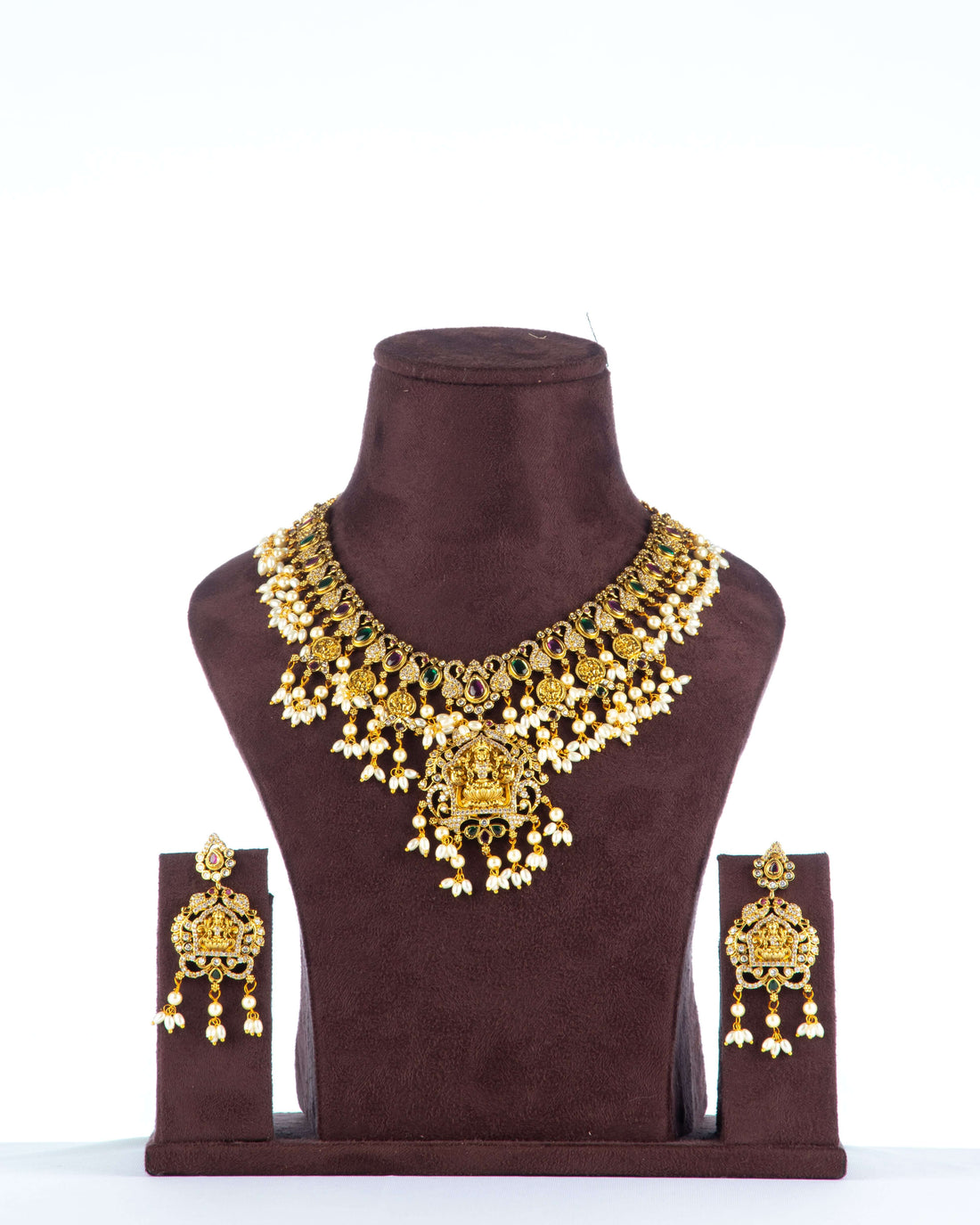 A Multi-Strand Choker Set with a Polki Diamond and Emerald Pendant displayed on a mannequin. The set has gold-colored strands of pearls and beads with a central emerald pendant.