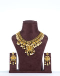 A Multi-Strand Choker Set with a Polki Diamond and Emerald Pendant displayed on a mannequin. The set has gold-colored strands of pearls and beads with a central emerald pendant.