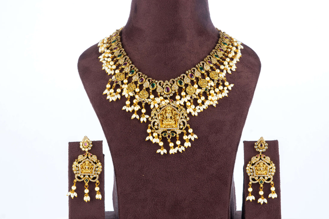 A Multi-Strand Choker Set with a Polki Diamond and Emerald Pendant displayed on a mannequin. The set has gold-colored strands of pearls and beads with a central emerald pendant.