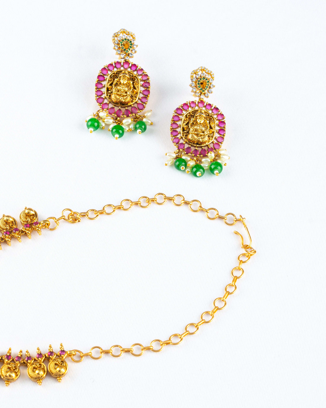 A South Indian coin necklace with a Goddess Laxmi pendant displayed on a mannequin bust, accompanied by a pair of matching earrings.