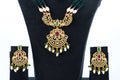 A full beaded necklace set with green beads and an ornate gold-toned pendant is displayed on a black jewelry bust. The pendant is adorned with red and green stones, and the set includes a pair of matching earrings with dangling pearl and green bead drops.
