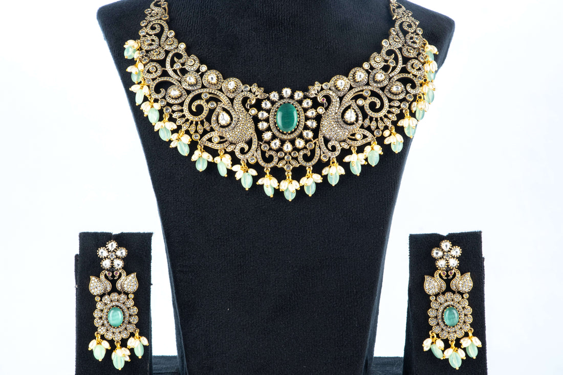 A Victorian-style beaded necklace with a black pendant, featuring vibrant green beads and intricate gold detailing, displayed on a mannequin bust.