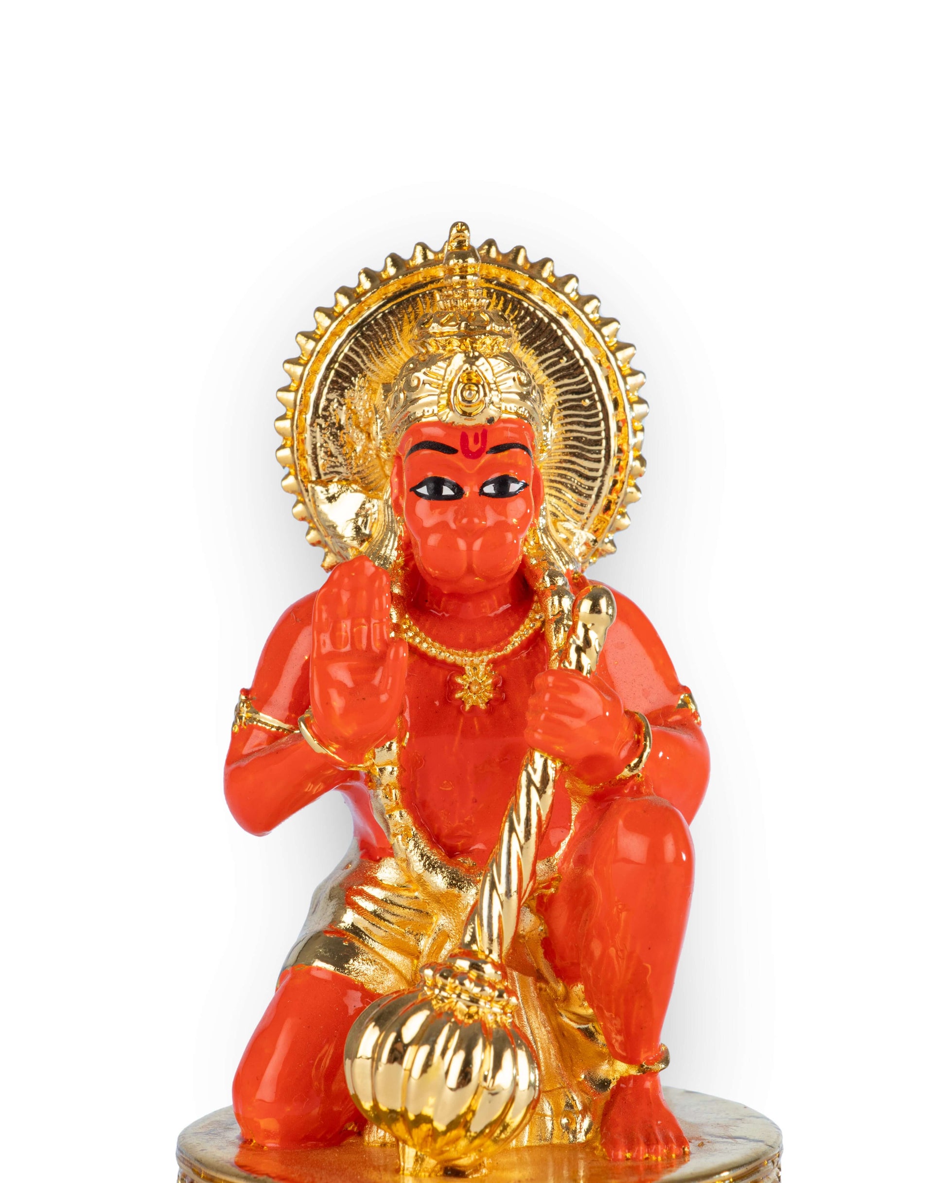 A vibrant orange-red and gold statue of a deity, likely Lord Hanuman, is shown kneeling on a golden, ornate base. The deity is holding a golden mace (gada) in one hand and raising the other in a gesture of blessing. The statue is adorned with a golden crown and ornaments and is surrounded by a golden halo.
