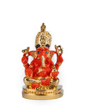 A close-up of a 3-inch Siddhivinayak Ganesh idol, which is gold-plated and features a glossy orange-red finish. The deity's trunk is turned to the right, and the idol is seated on a round, golden base. The idol is associated with the Hindu temple Shree Siddhivinayak Ganapati Mandir in Mumbai, India. The idol is considered a symbol of good fortune, wisdom, and success.