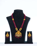 A beaded long necklace set with intricate gold-colored temple jewelry pendant and coordinating earrings, displayed on a mannequin bust.