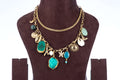 A double-layered chunky agate necklace, featuring two large, irregularly shaped teal-colored agate pendants as the focal points. The gold-toned chain is adorned with various charms, including seashells, starfish, and a sun, giving it a beach-inspired aesthetic. The necklace is displayed on a brown jewelry bust.