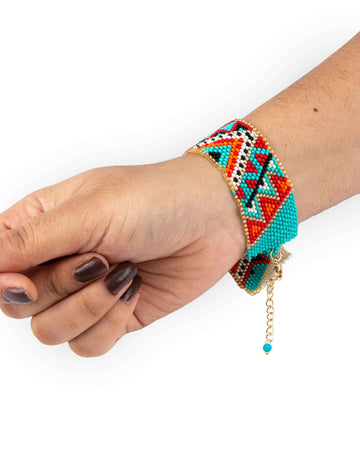 A colorful beaded bracelet on a person's wrist, featuring a vibrant palette with various colored beads and a gold-tone charm.