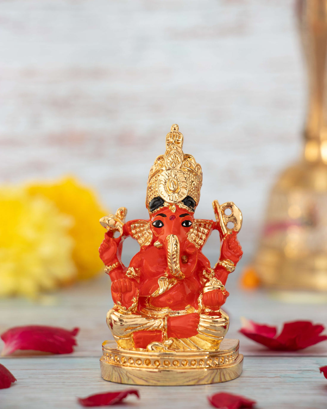 A vibrant red and gold colored statue of Lord Ganesha, seated, wearing a golden crown and ornaments.