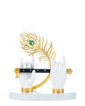 A decorative showpiece featuring two white hands holding a black flute, with a golden peacock feather adorned with a prominent blue jewel behind them, all mounted on a white circular base with golden accents at the wrists and around the flute holders.