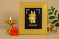 A close-up shot of a gold photo frame featuring a golden idol or depiction of Radha and Krishna, with