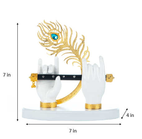 A Lord Krishna hand idol featuring two white hands adorned with gold-plated bracelets, holding a black flute, with a vibrant gold and blue peacock feather behind it. The idol stands on a white base, and the image includes annotations indicating its dimensions: 7 inches in height, 7 inches in width, and 4 inches in depth.