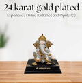 A 24-karat gold plated Ganesha idol with white and gold accents, sitting on a black base that reads